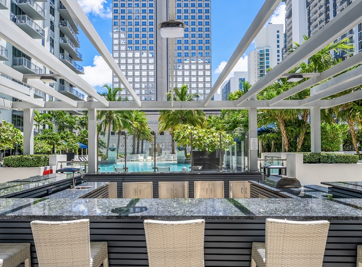 A pool surrounded by chairs and a white pergola.
